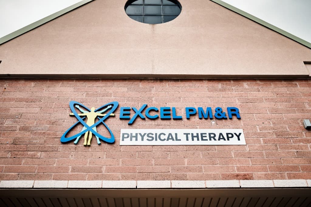 Excel PM&R Physical Therapy sign on the building's brick exterior