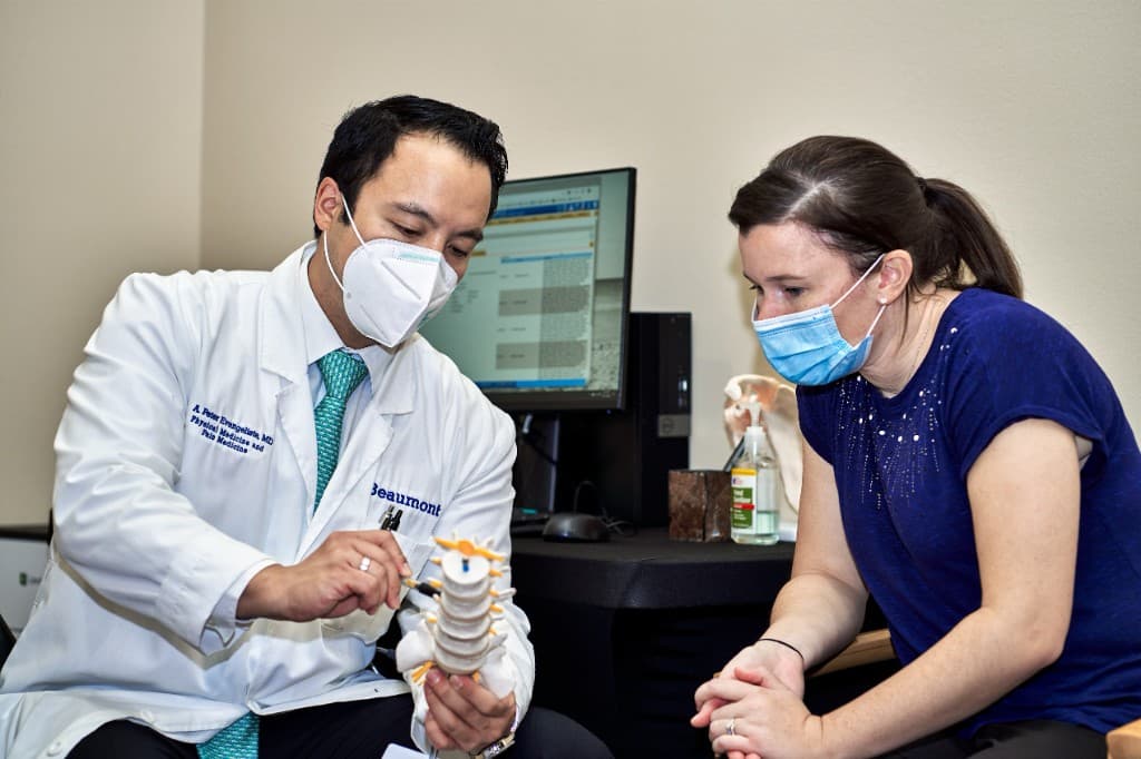 Physician reviewing a lumbar spine model with a patient during a consultation